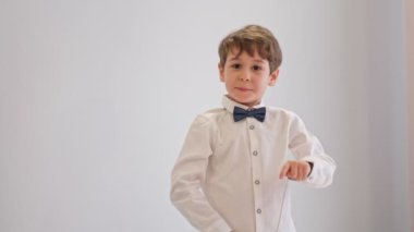 Şaşırmış küçük şirin çocuk, beyaz duvara karşı ön parmaklarıyla işaret ediyor, ağzı açık kalıyor ve şok oluyor. Reklam kavramı.