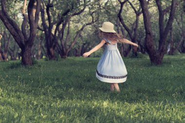 Mavi elbiseli bir kızın arkasından manzara parkta ya da ormanda yalınayak koşuyor. Dikkatsiz yaşam kavramı. Rüzgarda uçuşan saçlar