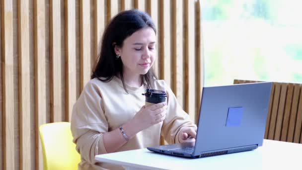 Mulher jovem hipster sentado no café, beber café e usando laptop.On mesa é laptop. Menina navegando na internet, conversando, blogging. — Vídeo de Stock