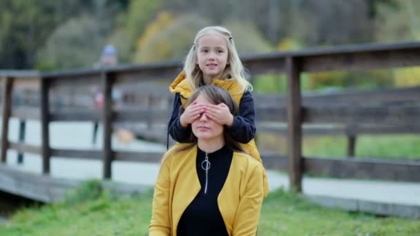 Beautiful young woman and her charming little daughter have fun in the park. Daughter hugging mother on nature. Slow motion video. stock footage — Stock Video