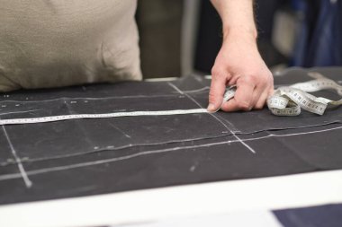 Terzi kadın işyeri. Terzi kadın, terzi stüdyosunda elbise dikmek için tebeşirle desen çiziyor. Terzi atölyesi, el yapımı özel elbiseler dikmek ve tamir etmek. yaratıcı meslek kavramı