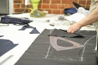 Terzi kadın işyeri. Terzi kadın, terzi stüdyosunda elbise dikmek için tebeşirle desen çiziyor. Terzi atölyesi, el yapımı özel elbiseler dikmek ve tamir etmek. yaratıcı meslek kavramı