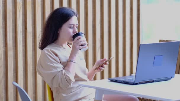 Mulher jovem hipster sentado no café, beber café e usando laptop.On mesa é laptop. Menina navegando na internet, conversando, blogging. — Vídeo de Stock