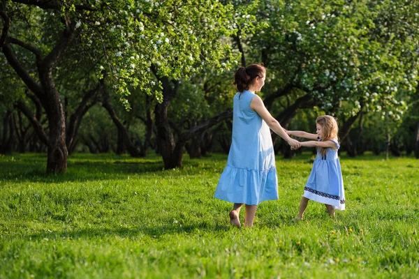 Naturszene mit familiärem Outdoor-Lifestyle. Mutter und kleine Tochter spielen zusammen in einem Park. Glückliches Familienkonzept. Glück und Harmonie im Familienleben. — Stockfoto