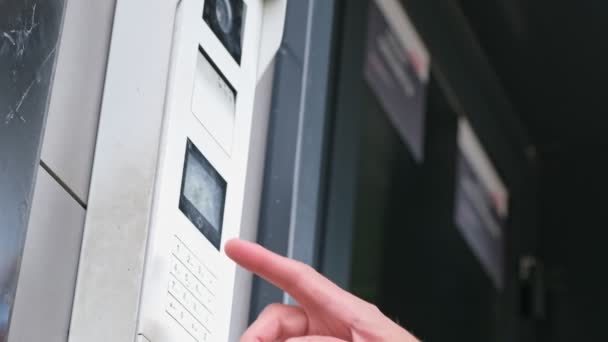Man använder intercom vid ingången till bostadshus. öppnar elektroniskt kodlås. man hand in säkerhetskod, trycka på knappen med pekfingret intercom enhet entré dörr. — Stockvideo