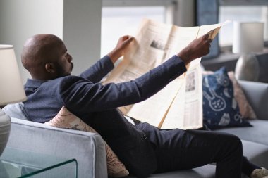 Elinde gazeteyle rahatlayan bir adam. Çekici adam haberleri okuyor..
