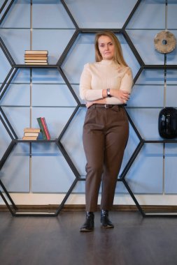 İyi görünümlü orta yaşlı kadın yönetici ofiste kolları bağlı duruyor..