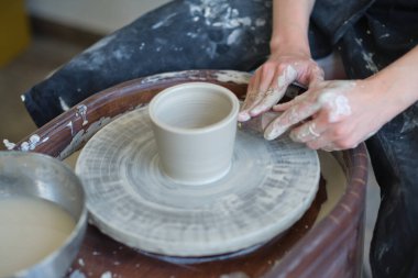 Kapalı kadın elleri kilden yemek yapar. Kadın elleri çömlekçi çarkında çalışıyor. Usta çömlekçi bir atölyede çalışıyor.