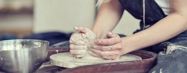 현수막을 닫고, 여자 손은 진흙으로 접시를 만든다. 수작업으로 토스터 휠을 만들고 있는 여성 손. 도공 이 작업장에서 일한다 — 스톡 사진