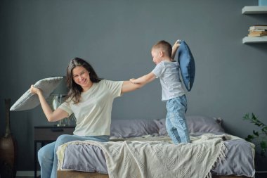 Anne, küçük oğluyla birlikte yatakta oynuyordu. Aile anları, çocukların bakımı. Annelik, annelik izni kavramı