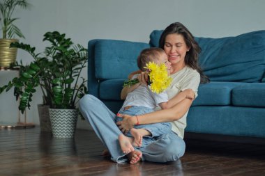 Anneler Günün kutlu olsun. Çocuk evlat tatilde annesini tebrik eder ve çiçek verir. Evde bayram kutlamaları sırasında anneler günü için onu tebrik etmek.