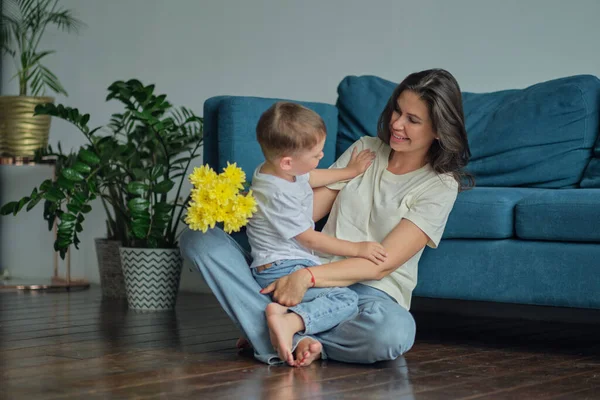 Grattis på mors dag. barn son gratulerar mor på semester och ger blommor. Familjeanknytning, moderskap — Stockfoto