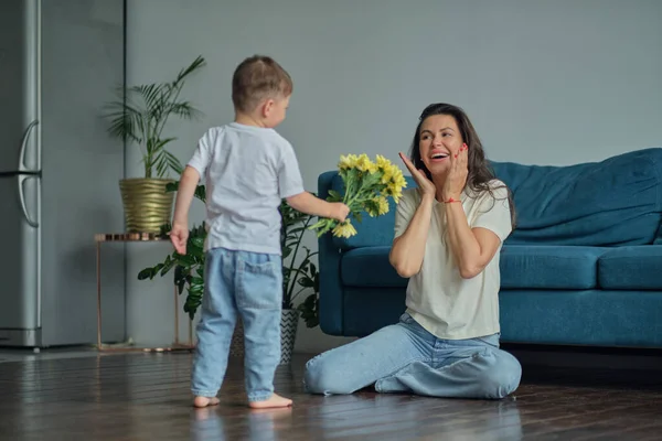 Bonne fête des mères. enfant fils félicite mère en vacances et donne des fleurs. Lien familial, maternité — Photo