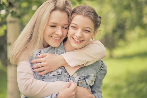 Mère heureuse avec sa fille embrassant un adolescent en été. Soins mère heureuse profiter de la journée avec l'adolescente enfant, rire avoir du plaisir. Mère donnant des conseils à sa fille. — Photo