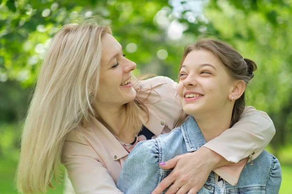 Eine glückliche Mutter mit ihrer Tochter, die im Sommer einen Teenager umarmt. Fürsorgliche glückliche Mutter genießen Tag mit Teenager-Mädchen Kind, lachen Spaß haben. Mutter gibt ihrer Tochter Rat. — Stockfoto