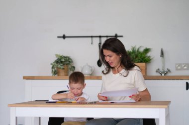 Küçük çocuk resim yapmayı öğreniyor. Anne ve oğlu kalemlerle çizim yaparken eğleniyor. Çocukların yaratıcılığı.