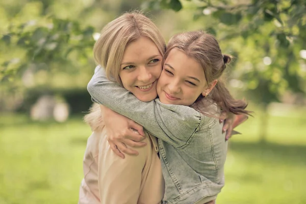 Mère heureuse avec sa fille embrassant un adolescent en été. Soins mère heureuse profiter de la journée avec l'adolescente enfant, rire avoir du plaisir. Mère donnant des conseils à sa fille. — Photo