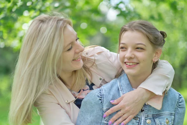 Lycklig mamma med sin dotter kramar en tonåring på sommaren. Vårda lycklig mor njuta av dagen med tonåring flicka barn, skratta ha kul. Mor ger sin dotter råd. — Stockfoto