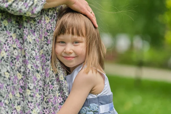 Velmi roztomilá malá blondýnka dívka s úsměvem a objímání její matka noha v retro barevném tónu — Stock fotografie