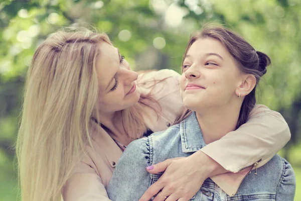 Gelukkige moeder met haar dochter knuffelen een tiener in de zomer. Zorgzame gelukkige moeder genieten van de dag met tienermeisje kind, lachen veel plezier. Moeder geeft haar dochter advies. — Stockfoto