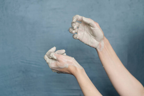 female hands clotted mud clay play cheerfully and show hands. Hands dirty