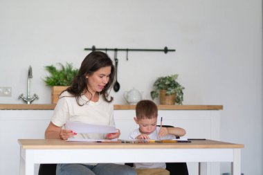 Küçük çocuk resim yapmayı öğreniyor. Anne ve oğlu kalemlerle çizim yaparken eğleniyor. Çocukların yaratıcılığı.
