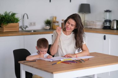 Küçük çocuk resim yapmayı öğreniyor. Anne ve oğlu kalemlerle çizim yaparken eğleniyor. Çocukların yaratıcılığı.