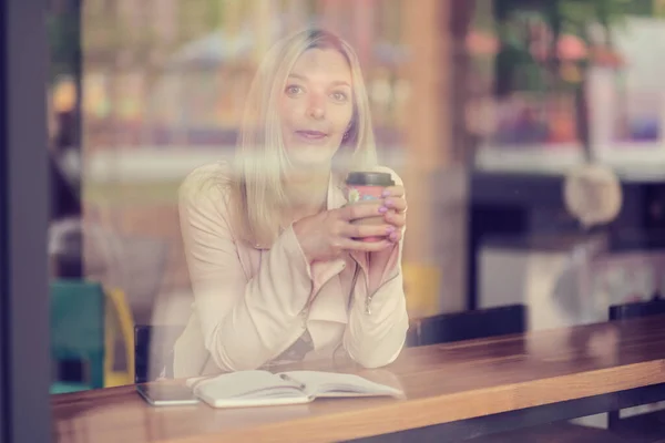 A mulher no café senta-se em uma mesa, bebe o café e olha afastado. tom de cor vintage — Fotografia de Stock