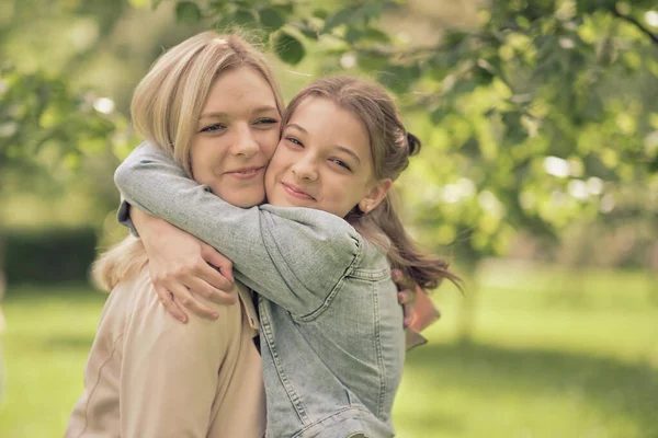 Lycklig mamma med sin dotter kramar en tonåring på sommaren. Vårda lycklig mor njuta av dagen med tonåring flicka barn, skratta ha kul. Mor ger sin dotter råd. — Stockfoto