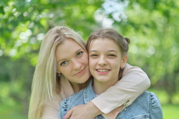 Eine glückliche Mutter mit ihrer Tochter, die im Sommer einen Teenager umarmt. Fürsorgliche glückliche Mutter genießen Tag mit Teenager-Mädchen Kind, lachen Spaß haben. Mutter gibt ihrer Tochter Rat. — Stockfoto