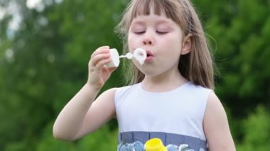 Bahar parkında karahindiba üfleyen sevimli küçük bir kız. Mutlu çocuk dışarıda eğleniyor..