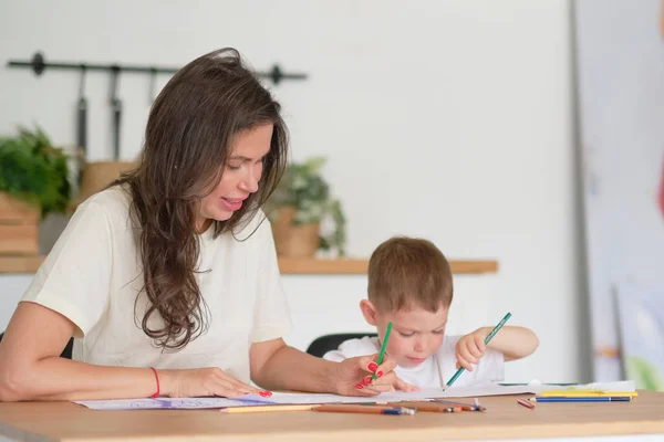 少年は絵を描くことを学ぶ。お母さんと息子は鉛筆で楽しく絵を描く。子供の創造性. — ストック写真
