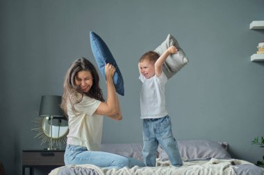 Anne, küçük oğluyla birlikte yatakta oynuyordu. Aile anları, çocukların bakımı. Annelik, annelik izni kavramı