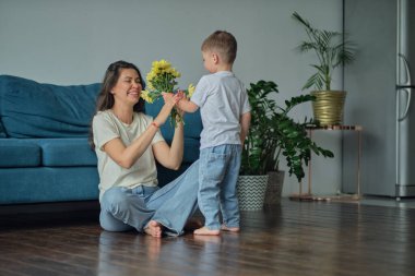 Anneler Günün kutlu olsun. Çocuk evlat tatilde annesini tebrik eder ve çiçek verir. Evde bayram kutlamaları sırasında anneler günü için onu tebrik etmek.