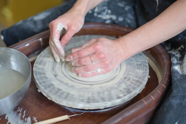 Close up female hands make dishes from clay. woman hands working on potters wheel. The master potter works in a workshop — Stock Photo, Image