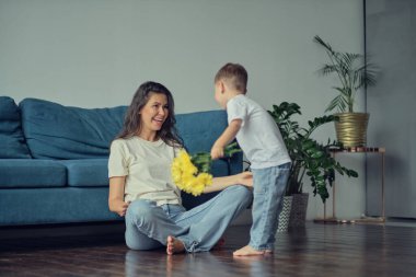 Anneler Günün kutlu olsun. Çocuk evlat tatilde annesini tebrik eder ve çiçek verir. Evde bayram kutlamaları sırasında anneler günü için onu tebrik etmek.