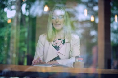 Kafedeki kadın bir masaya oturur, kahve içer ve gözlerini kaçırır. Klasik renk tonu