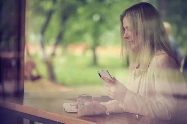 Café mulher estilo de vida da cidade no telefone beber café mensagem de texto SMS no aplicativo smartphone sentado em interior no moderno café urbano. em tom de cor vintage — Fotografia de Stock
