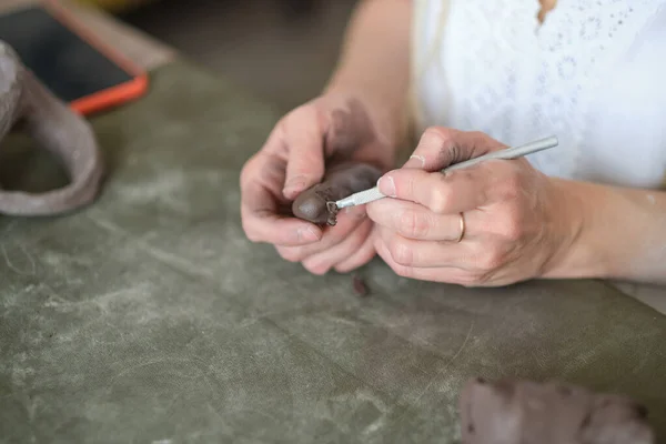 陶芸家の家庭教師。女性の手は灰色の粘土の一部を振る。自分の手で粘土で作られた陶器。灰色のボールを保持 — ストック写真