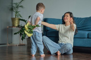 Anneler Günün kutlu olsun. Çocuk evlat tatilde annesini tebrik eder ve çiçek verir. Evde bayram kutlamaları sırasında anneler günü için onu tebrik etmek.