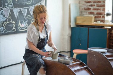 Dişi Potter çömlekçi çarkında toprak kavanozu yaratıyor.