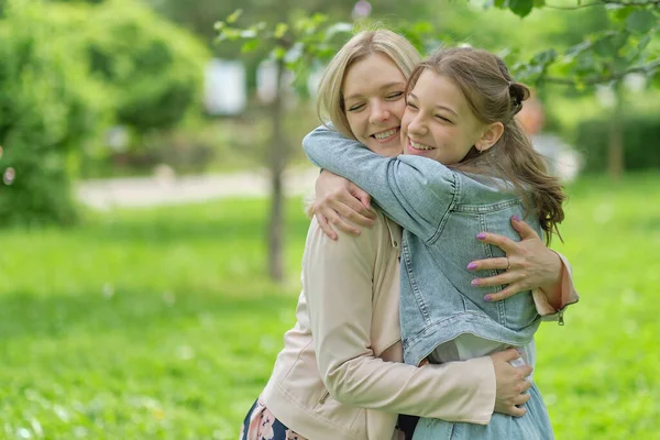 Mãe feliz com sua filha abraçando um adolescente no verão. Cuidar da mãe feliz desfrutar do dia com a criança adolescente, rir se divertir. Mãe dando conselhos à filha. — Fotografia de Stock