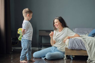 Anneler Günün kutlu olsun. Çocuk evlat tatilde annesini tebrik eder ve çiçek verir. Aile bağı, annelik.