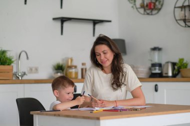 Küçük çocuk resim yapmayı öğreniyor. Anne ve oğlu kalemlerle çizim yaparken eğleniyor. Çocukların yaratıcılığı.
