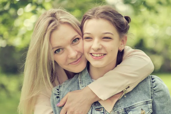 Mère heureuse avec sa fille embrassant un adolescent en été. Soins mère heureuse profiter de la journée avec l'adolescente enfant, rire avoir du plaisir. Mère donnant des conseils à sa fille. — Photo