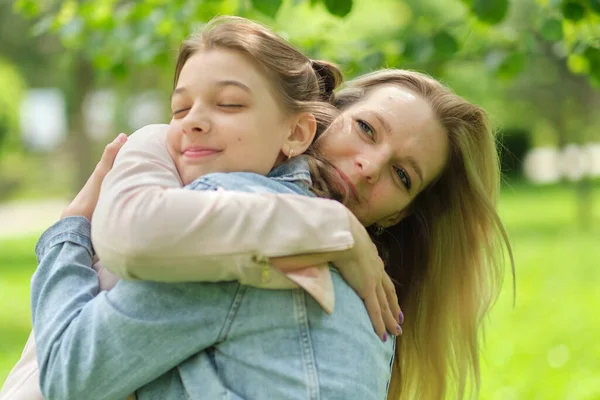 Mãe feliz com sua filha abraçando um adolescente no verão. Cuidar da mãe feliz desfrutar do dia com a criança adolescente, rir se divertir. Mãe dando conselhos à filha. — Fotografia de Stock