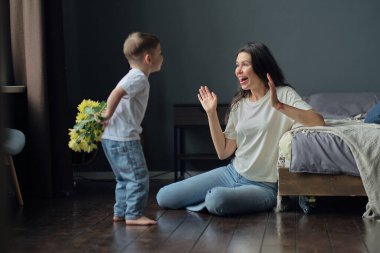 Anneler Günün kutlu olsun. Çocuk evlat tatilde annesini tebrik eder ve çiçek verir. Evde bayram kutlamaları sırasında anneler günü için onu tebrik etmek.