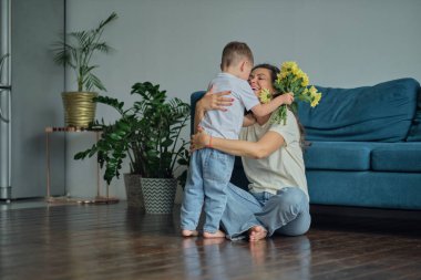 Anneler Günün kutlu olsun. Çocuk evlat tatilde annesini tebrik eder ve çiçek verir. Evde bayram kutlamaları sırasında anneler günü için onu tebrik etmek.