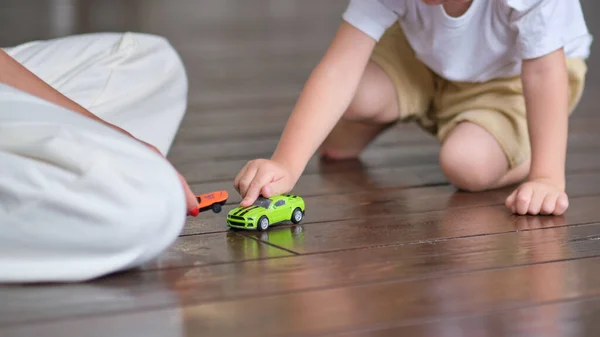 Uttrycksfull pojke leker med en leksaksbil med mamma. — Stockfoto