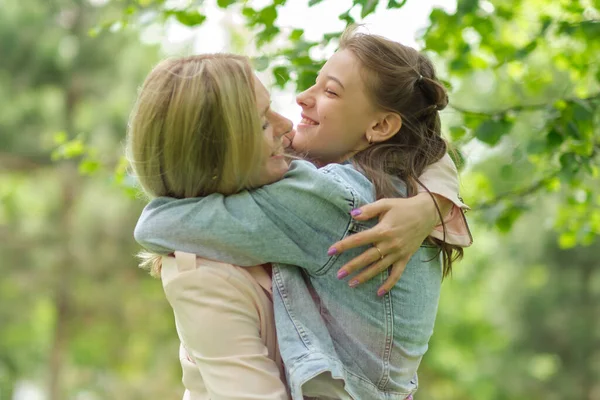 Mère heureuse avec sa fille embrassant un adolescent en été. Soins mère heureuse profiter de la journée avec l'adolescente enfant, rire avoir du plaisir. Mère donnant des conseils à sa fille. — Photo